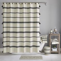 a white and black shower curtain next to a bath tub with a rug on the floor