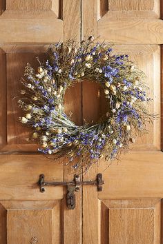 a wreath hanging on the front door of a house with blue and white flowers in it