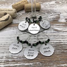 wine glass charms with words on them sitting next to corks