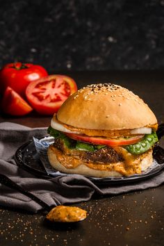 a cheeseburger with lettuce, tomato and onion on a black plate