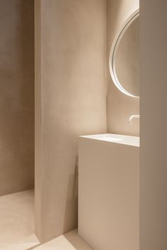 a white sink sitting under a round mirror in a bathroom next to a wall mounted faucet