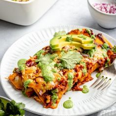 a white plate topped with lasagna covered in guacamole and avocado