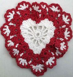 a crocheted red and white doily with a heart on it's center