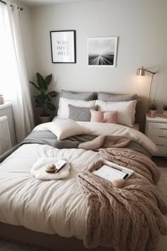 a bed with blankets and pillows on top of it in a bedroom next to a window