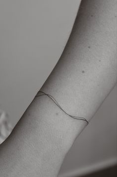 a woman's arm with a single line tattoo on it