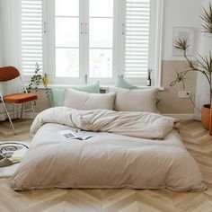 an unmade bed sitting in front of two windows