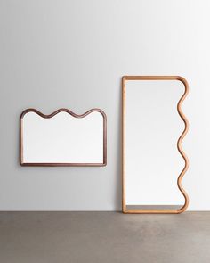 two mirrors on the wall next to each other and one has a wooden frame in it