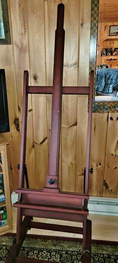 an easel leaning against a wooden wall in a room with wood paneled walls