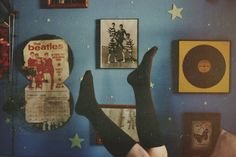 a woman laying on her back in front of a wall covered with pictures and records