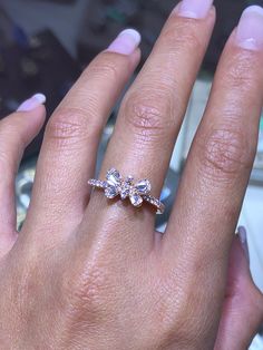 a woman's hand with a diamond ring on top of her finger and the other hand holding an engagement ring