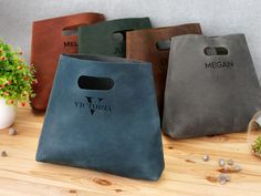 three different colored bags sitting on top of a wooden table next to a potted plant