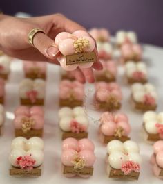 a person holding up a tiny ring in front of small desserts on a table