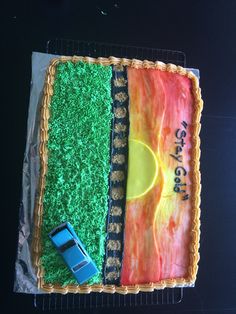 a birthday cake decorated with grass and a car