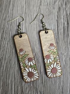 Make a statement while wearing these lightweight wood hand painted floral dangle earrings. Boho chic style is all the rage now!  Super light and comfortable.  unique open cut design. These make great gifts also!   Approximate measurements:  .6" wide 2" tall 2.75" total length with hardware Product Details: Earrings are made out of 1/8" thick birch with hand painted engraved flowers.  Wire ear hooks are hypoallergenic and antique bronze in color. Turn around time is usually about 2-3 business day Woodburned Earrings, Laser Earrings, Earrings Boho Chic, Engraving Ideas, Engraved Flower, Dangle Earrings Boho