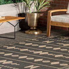 a black and white rug with arrows on it next to a chair, table and potted plant