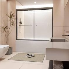 a bathroom with a sink, toilet and bathtub next to a plant in the corner