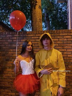 a man and woman dressed in costumes standing next to each other with a red balloon