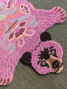 a pink bear rug on the ground with it's paw sticking out from its mouth