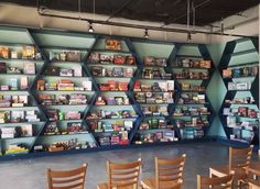 a room filled with lots of books on shelves next to wooden chairs and tables in front of them