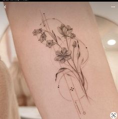 a tattoo with flowers on the side of a woman's leg and an arrow in the middle