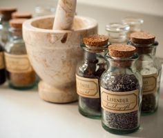 bottles filled with spices sitting on top of a counter next to jars and mortars