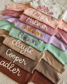 there are many different colors of socks on the bed with words written on them in cursive writing