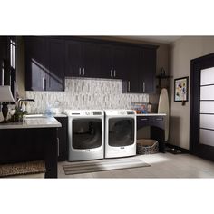 a washer and dryer in a kitchen with dark wood cabinets, white tile flooring