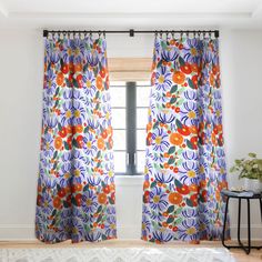 an open window with colorful curtains in front of it and a rug on the floor