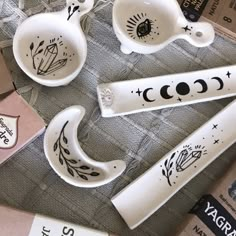 ceramic bowls and spoons with designs on them are sitting on a tablecloth next to other items