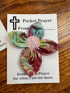 two small flower brooches on top of a card with the words pocket prayer from sendit us prayer for when i am not there