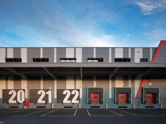 an empty parking lot in front of a building with red doors and numbers on it