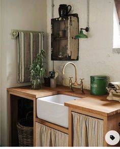 a kitchen sink sitting under a window next to a counter top with a potted plant on it