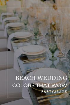 a long table with white plates and gold rimmed glasses on it is set for an elegant beach wedding