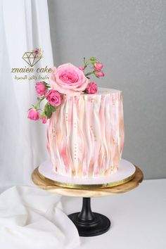 a white cake with pink flowers on top sitting on a gold plated platter