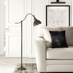 a living room with a white couch, black and white pillows and a gold floor lamp