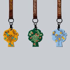 three key chains with different designs and colors on each lanyard, one has a name tag attached to it