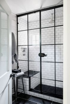 a black and white photo of a bathroom with glass shower doors that open to the outside