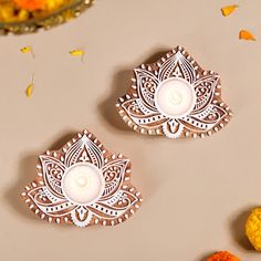 two decorative candles sitting on top of a table next to oranges and other decorations