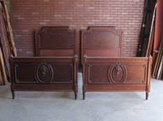 two wooden beds sitting next to each other in front of a brick wall