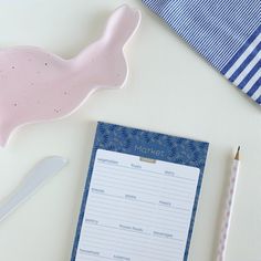 a notepad with a pink fish on it next to a blue striped napkin and pencil