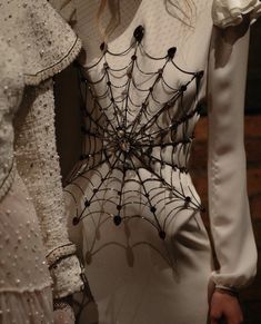 the back of a woman's dress with spider webs and pearls on it