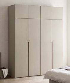 a bed sitting next to a tall white cabinet