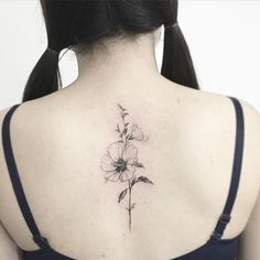 the back of a woman's neck with a flower tattoo on it