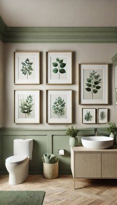 a bathroom with green walls and pictures on the wall above the toilet, sink and mirror