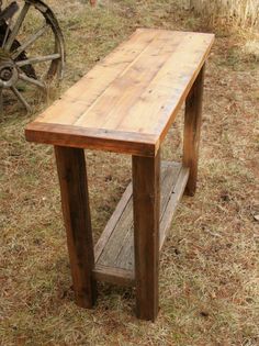 a wooden table sitting on top of a dry grass field next to an old wagon