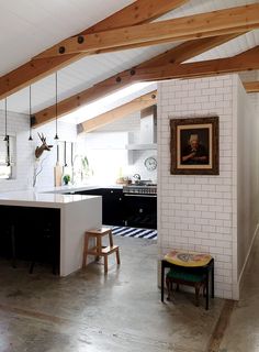 an open kitchen and living room with exposed beams on the ceiling, along with white brick walls