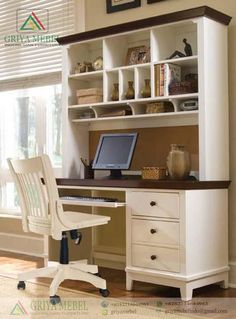 a desk with a computer on top of it in front of a window and white chairs