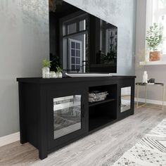 a black entertainment center with mirrored doors and drawers in a living room next to a window