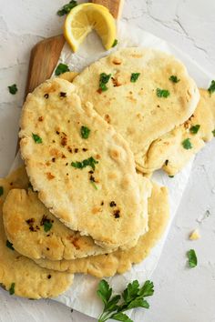 some flat breads are stacked on top of each other with lemon wedges next to them