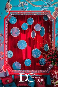 a red and blue wall with decorative plates on it, in front of a couch